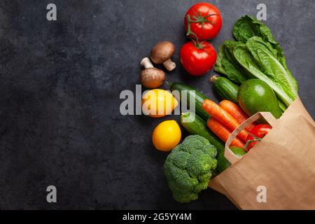 Cibo diverso nel sacchetto di carta di riciclaggio su tavola di pietra. Vista dall'alto in piano con spazio per la copia Foto Stock