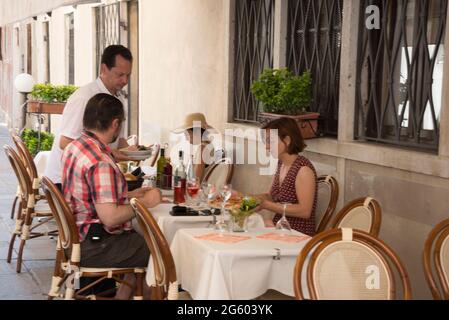 Un paio di turisti che vengono serviti pizze in un piccolo ristorante lungo il Rio Tera San Leonardo a Cannaregio, una strada popolare con i turisti, Foto Stock