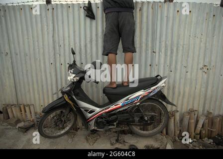 Un pescatore ricreativo in piedi su una motocicletta per pescare su uno stagno situato in un'area chiusa nella zona costiera di Giacarta a Marunda, Cilincing, North Jakarta, Jakarta, Indonesia. Foto Stock