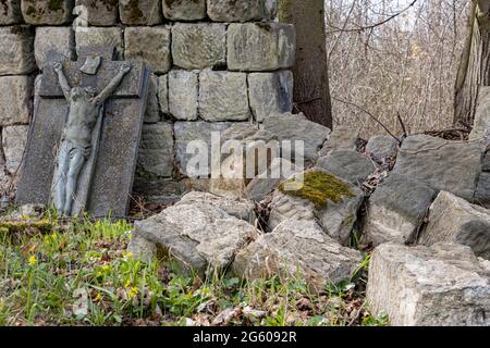 Un muro di pietra demolito con una lapide danneggiata in un cimitero Foto Stock