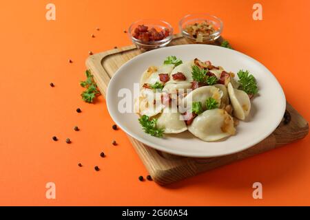 Concetto di cibo gustoso con vareniki o pierogi su sfondo arancione Foto Stock