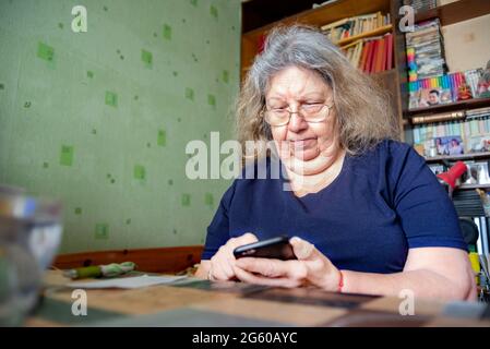 Serious anziano Ebraico sovrappeso Signora a casa digitando al telefono Foto Stock