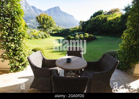 Vista generale di tavolo e sedie in vimini sulla terrazza con splendida vista sulla campagna delle montagne Foto Stock