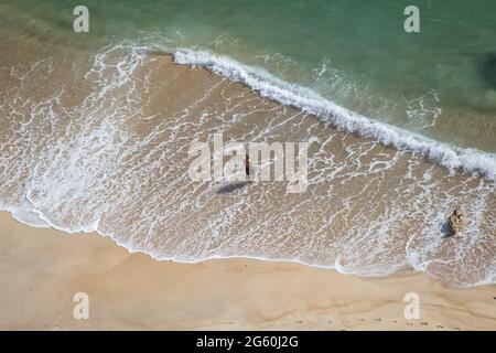 Vista aerea dell'uomo anziano che entra nell'acqua di mare con debole ondulazione. Persona isolata dalla schiena nel mare pulito, oceano Atlantico, Algarve, Portogallo. Foto Stock