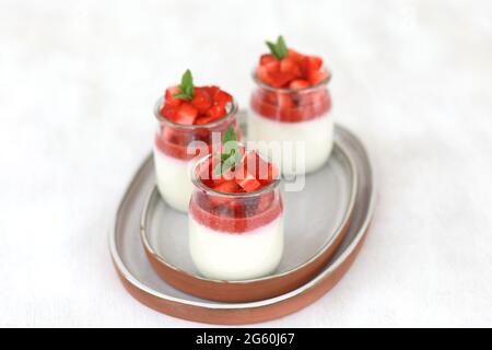Panna cotta da dessert italiano con gelatina di frutta e fragole fresche su sfondo bianco. Spazio di copia Foto Stock