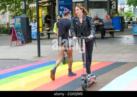 Bristol, Regno Unito. 1 luglio 2021. Bristol inizia a celebrare il mese del Pride rivernendo un attraversamento pedonale nei colori arcobaleno del movimento dell'orgoglio LGBTQ. La moda vivace e gli scooters elettronici sono anche molto Bristol cosa. Credit: JMF News/Alamy Live News Foto Stock