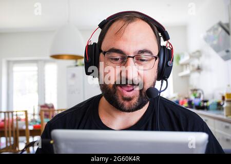 Giovane adulto in cuffia che parla con la webcam Foto Stock