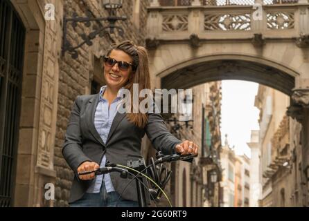 Ritratto di una donna d'affari di successo conduce a mano in bicicletta modo di casa per lavorare nella bella città vecchia centro Foto Stock