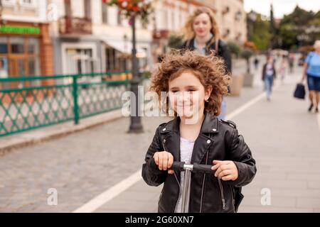 L'elegante bambina guida uno scooter in città Foto Stock