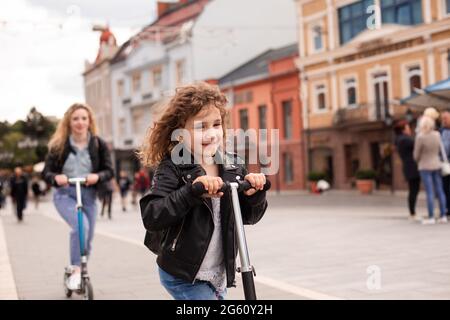 L'elegante bambina guida uno scooter in città Foto Stock