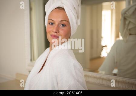 Ritratto di donna caucasica sorridente in bagno con asciugamano sulla testa Foto Stock