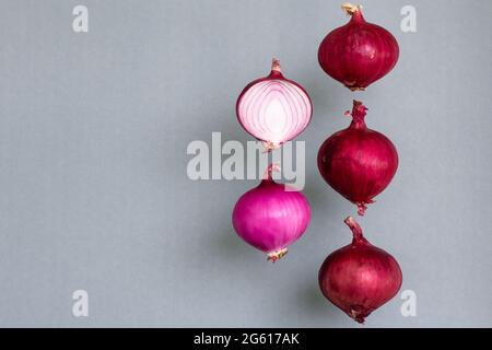 Cipolla viola, sia intera che tagliata appesa in aria su sfondo grigio e c'è ombra. Spazio di copia. Foto Stock