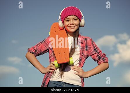 Stile di vita attivo. Skater ragazza attiva tenere penny bordo cielo soleggiato. Sport d'azione. Attività ricreative. Vita sana. Skateboard e trasporto Foto Stock