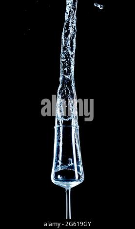 Spruzzi d'acqua con vetro rovesciato e sfondo nero. Foto Stock