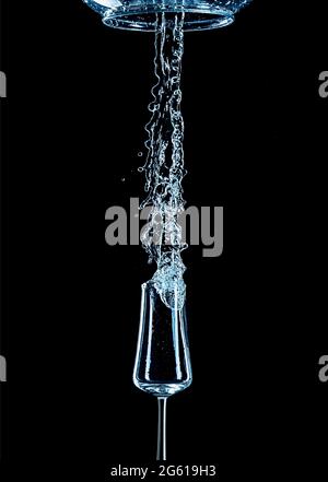 Spruzzi d'acqua con vetro rovesciato e sfondo nero. Foto Stock