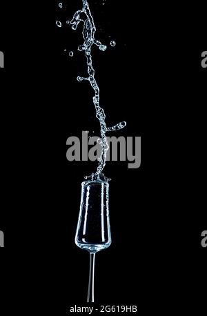 Spruzzi d'acqua con vetro rovesciato e sfondo nero. Foto Stock