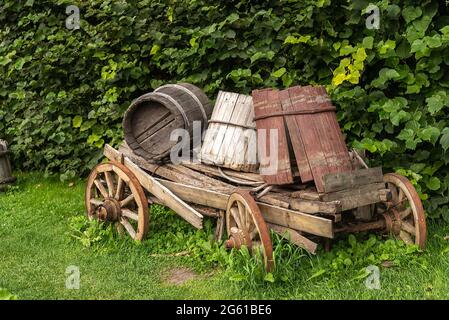 Carrello di punta in legno con barili rotti si erge su prato verde Foto Stock