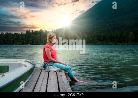 Giovane donna che si rilassa sul molo sul lago Foto Stock