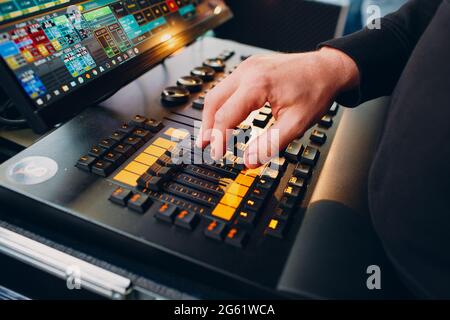 la mano del tecnico del suono sposta i cursori sulla console di mixaggio del suono durante lo spettacolo. Foto Stock