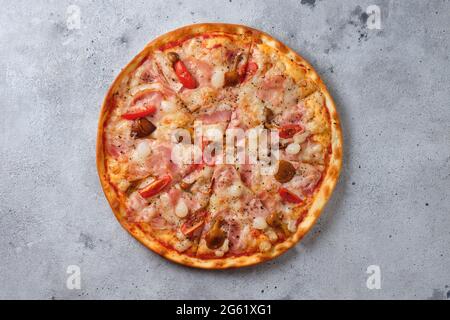 Pizza con pomodori, pancetta, cipolle sottaceto, funghi al miele, mozzarella, spezie e salsa di pomodoro. Disposizione piatta. Su uno sfondo chiaro Foto Stock