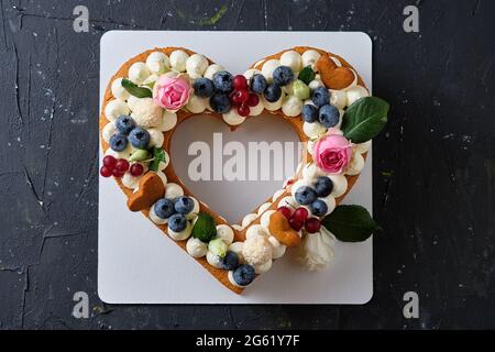 Torta al miele con mirtilli freschi, erbe e crema di formaggio. Dessert per una persona cara. Torta cuore. Foto Stock