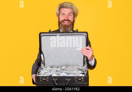 Uomo d'affari sorridente con valigetta con soldi. Uomo d'affari con valigia piena di dollari. Cassa con contanti. Ricchezza e ricchi. Foto Stock