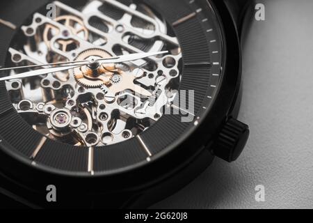 Orologio da polso scheletro con quadrante nero dell'orologio, foto macro. Si tratta di un orologio meccanico in cui tutte le parti in movimento sono visibili Foto Stock