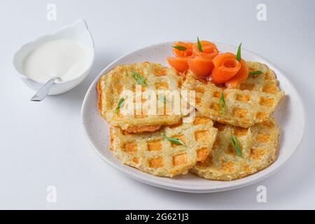 Abbondanti frittelle di patate con pesce rosso, guarnite con cipolle verdi fresche. Piatto su un piatto bianco. Foto Stock