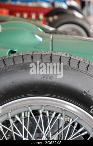 Ruota a raggi e pneumatico di un'auto classica. Auto da corsa d'epoca in garage paddock prima di partecipare all'evento storico Goodwood Revival, nel Regno Unito. Vecchia auto Foto Stock