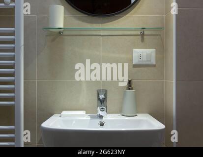 Primo piano di un lavandino di un bagno moderno con un ripiano in vetro e uno specchio sopra di esso. Foto Stock