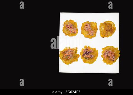 Dettaglio della degustazione di alcuni Totteri con insalata di carote grattugiate, cavolo, lattuga, maionese. I Patacones sono tipici della gastronomia caraibica Foto Stock