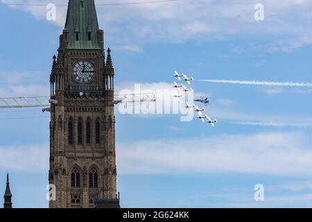 Ottawa, Ontario, Canada - 1 luglio 2021: Gli Snowbirds delle forze canadesi volano in formazione oltre la Peace Tower con un jet dimostrativo CF-18 il Canada Day. Foto Stock