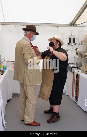 Windsor, Berkshire, Regno Unito. 1 luglio 2021. Simon Umfreville prova su un cappello alla stalla di Ascot Top Cappelli, ma a causa delle norme Covid-19 deve indossare un tappo doccia prima di provare il cappello. Il Villaggio commerciale era occupato questa mattina. Lo spettacolo del Cavallo si svolge questa settimana fino a domenica nell'Home Park all'interno dei terreni privati del Castello di Windsor, casa di sua Maestà la Regina Elisabetta II Credito: Maureen McLean/Alamy Foto Stock