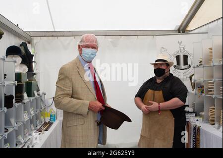 Windsor, Berkshire, Regno Unito. 1 luglio 2021. Simon Umfreville prova su un cappello alla stalla di Ascot Top Cappelli, ma a causa delle norme Covid-19 deve indossare un tappo doccia prima di provare il cappello. Il Villaggio commerciale era occupato questa mattina. Lo spettacolo del Cavallo si svolge questa settimana fino a domenica nell'Home Park all'interno dei terreni privati del Castello di Windsor, casa di sua Maestà la Regina Elisabetta II Credito: Maureen McLean/Alamy Foto Stock