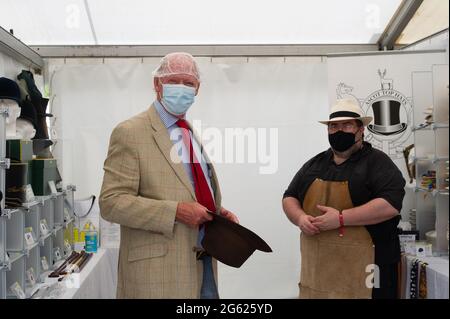 Windsor, Berkshire, Regno Unito. 1 luglio 2021. Simon Umfreville prova su un cappello alla stalla di Ascot Top Cappelli, ma a causa delle norme Covid-19 deve indossare un tappo doccia prima di provare il cappello. Il Villaggio commerciale era occupato questa mattina. Lo spettacolo del Cavallo si svolge questa settimana fino a domenica nell'Home Park all'interno dei terreni privati del Castello di Windsor, casa di sua Maestà la Regina Elisabetta II Credito: Maureen McLean/Alamy Foto Stock