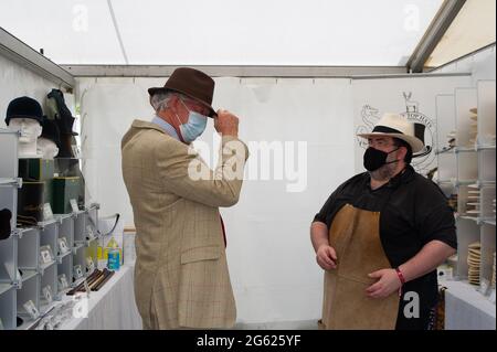 Windsor, Berkshire, Regno Unito. 1 luglio 2021. Simon Umfreville prova su un cappello alla stalla di Ascot Top Cappelli, ma a causa delle norme Covid-19 deve indossare un tappo doccia prima di provare il cappello. Il Villaggio commerciale era occupato questa mattina. Lo spettacolo del Cavallo si svolge questa settimana fino a domenica nell'Home Park all'interno dei terreni privati del Castello di Windsor, casa di sua Maestà la Regina Elisabetta II Credito: Maureen McLean/Alamy Foto Stock