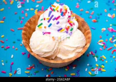 Gelato alla vaniglia in una ciotola con waffle su sfondo blu Foto Stock