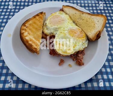 La colazione è composta da due uova su un terreno medio, oltre a patate di manzo e pane tostato. Foto Stock