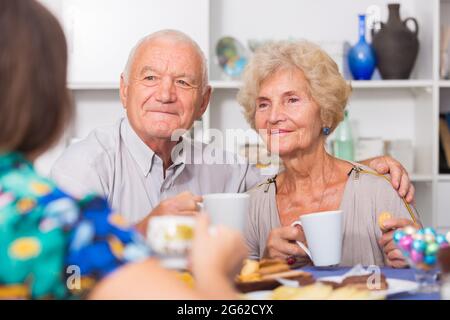 Felice coppia matura bevendo tè con ospite femminile Foto Stock