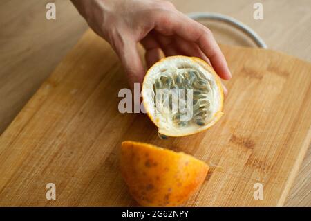 granadilla matura biologica fresca o frutto della passione gialla tagliato a metà su tavola di legno. Frutta esotica, concetto di alimentazione sana Foto Stock