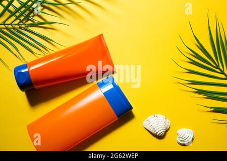 Due tubi con crema solare mock-up su uno sfondo estivo giallo. Protezione contro i raggi UV della pelle con filtro SPF, shampoo per la cura dei capelli e balsamo. A sa Foto Stock