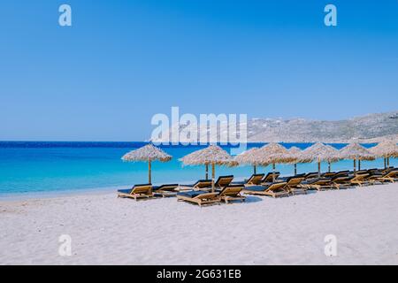 Elia Beach Mykonos, un giovane ragazzo sulla spiaggia di Mykonos durante l'estate con un ombrellone e sedie da spiaggia di lusso letti, l'oceano blu a Elia spiaggia Mykonos Grecia. Foto Stock