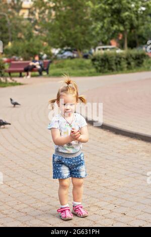 La bambina corre dopo i piccioni. Estate. Foto Stock