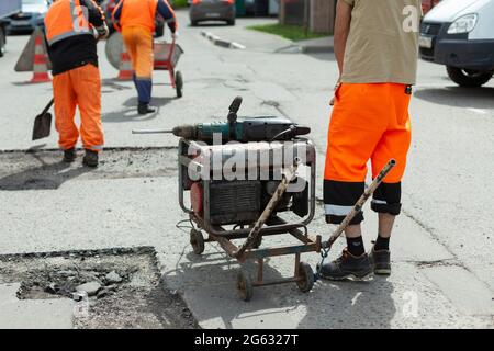 Generatore di benzina di elettricità. Alimentazione all'utensile elettrico. Generatore sulla strada per la riparazione stradale. Foto Stock