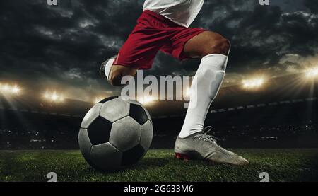 Calcio maschile corto, calcio calciatore allo stadio durante la partita sportiva su sfondo cielo scuro. Foto Stock