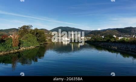 Panorama della città di Nelson, che si riflette nelle acque tranquille del fiume Maitai, Nuova Zelanda. Foto Stock