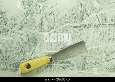 Cazzuola da costruzione sul tavolo durante il processo. Processo di ristrutturazione, sfondo con spazio per la copia. Coltello per stucco in un mastice sullo sfondo della parete Foto Stock