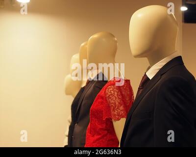 Manichini maschili e femminili senza volto in abiti e abiti si trovano in fila nel negozio Foto Stock