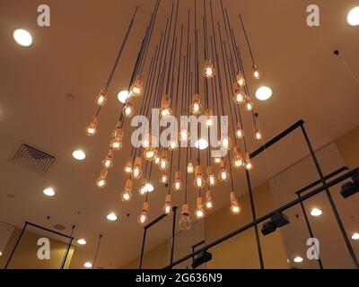 Molte lampadine incandescenti pendono dal soffitto. Illuminazione decorativa Foto Stock