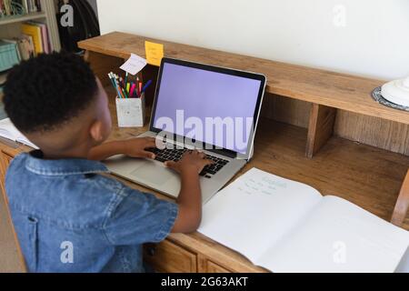 Ragazzo afroamericano che ha videochiamata usando il laptop durante la classe a casa Foto Stock